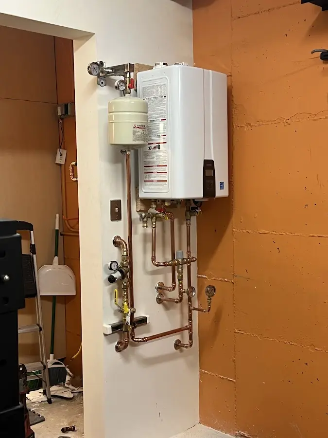 Plumbing technician inspecting water heater connections in West Point